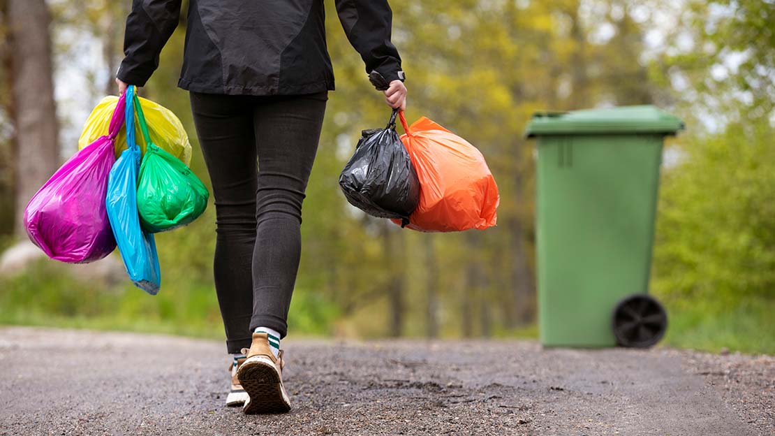 Person på väg att slänga färgsorterade påsar