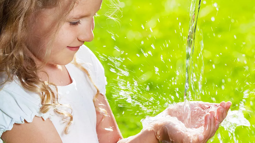 Flicka tar emot vatten i kupade händer