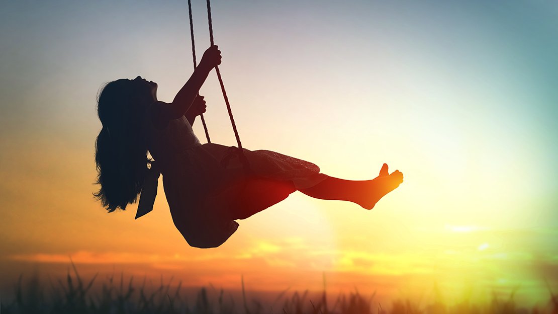 Flicka gungar i solnedgången