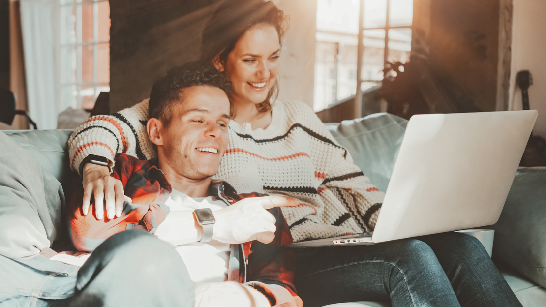 Bild på kille och tjej i soffa framför en dator