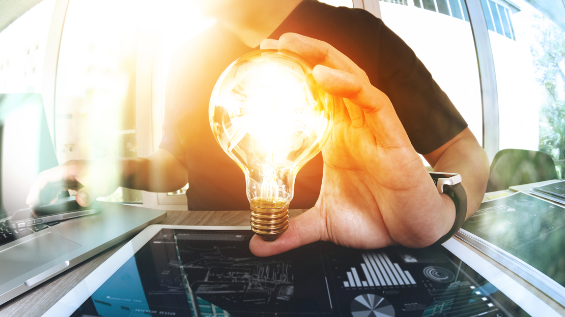 Hand håller i lysande glödlampa