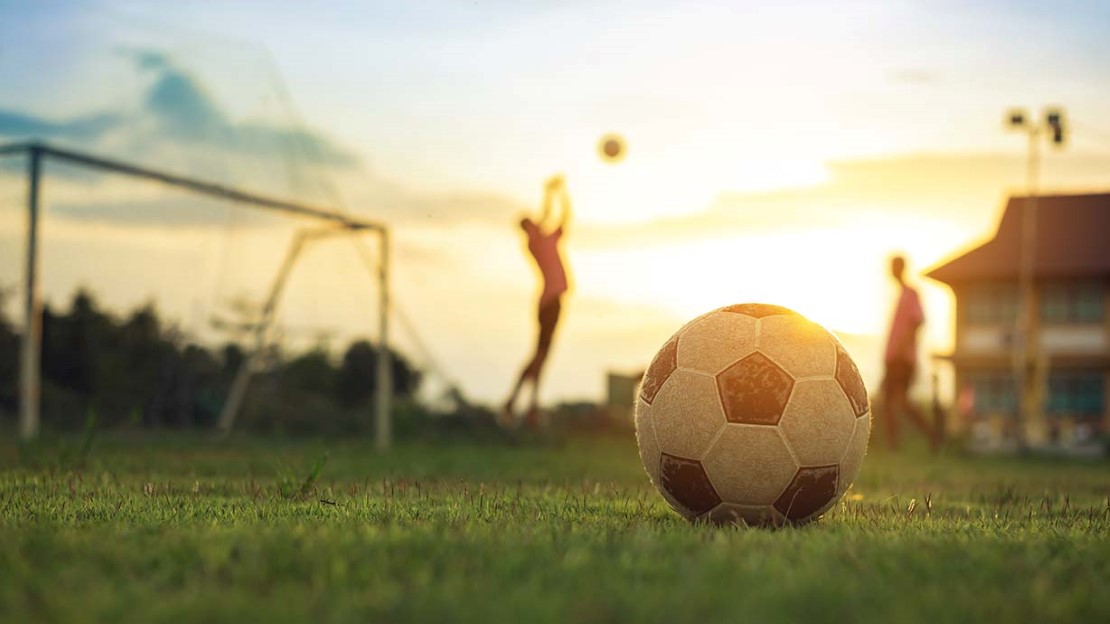 Fotboll med mål och två spelare i bakgrunden