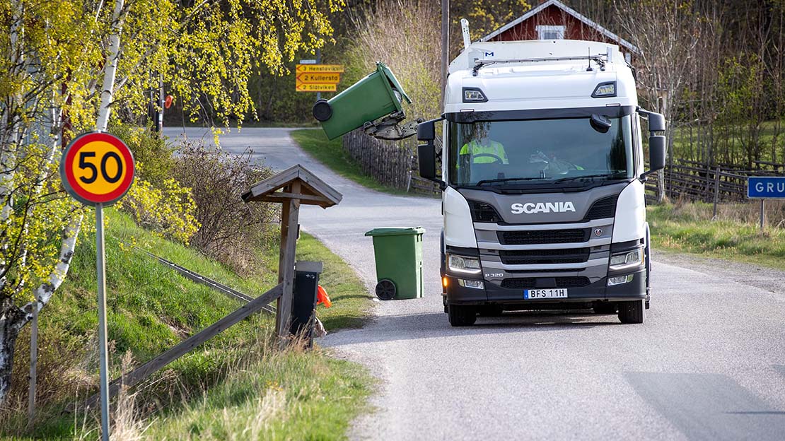 Sopbil med sidlastare tömmer ett sopkärl