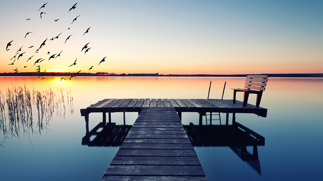 Brygga vid stilla sjö i solnedgång