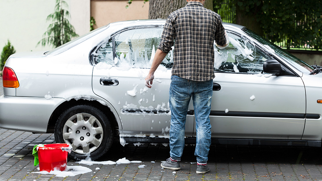 Man som tvättar bilen hemma