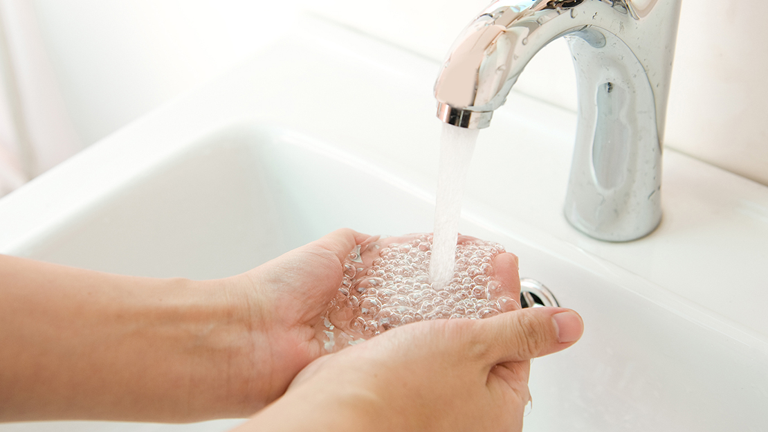 Kupade händer under vattenkran