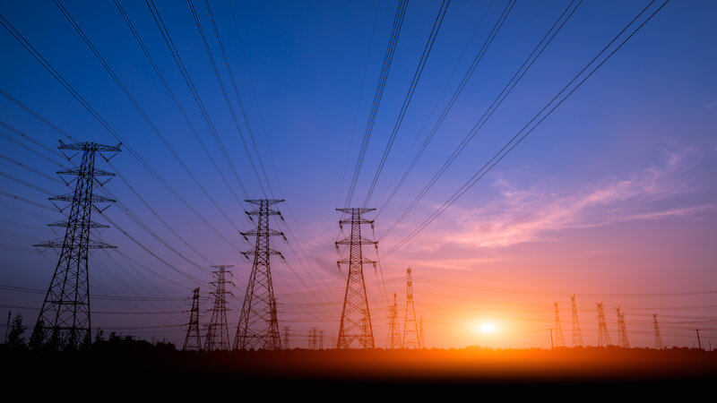 Många el-ledningar med solnedgång i bakgrunden