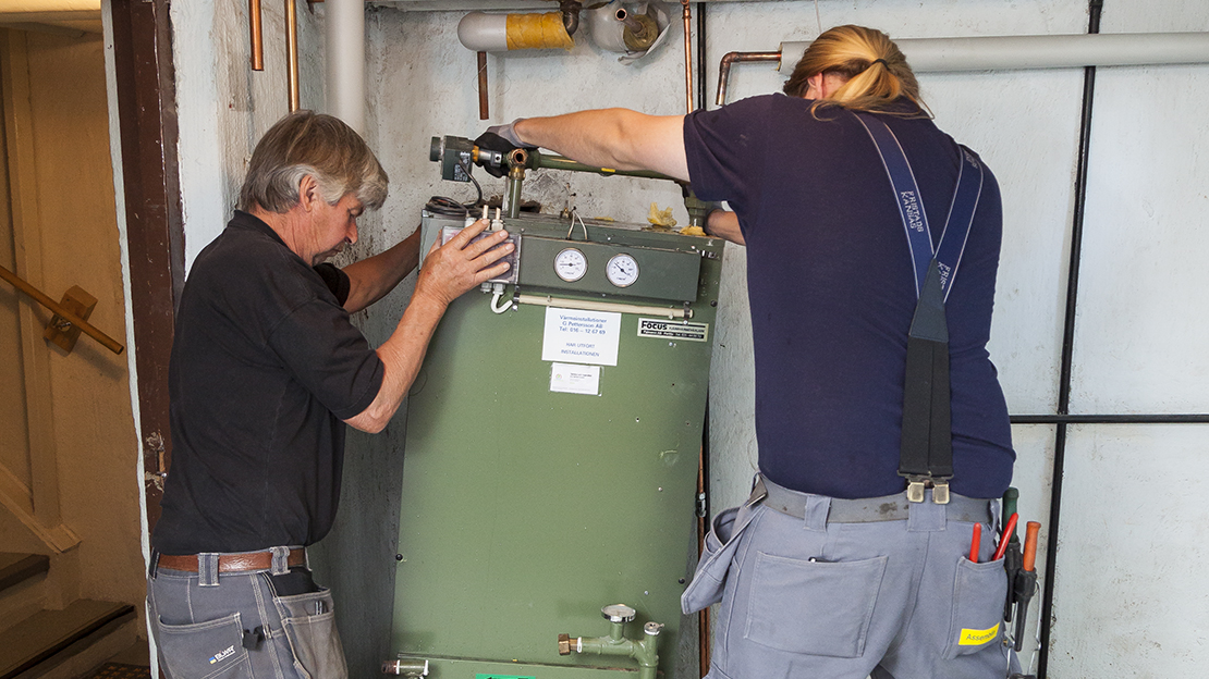 Två personer byter värmeväxlare